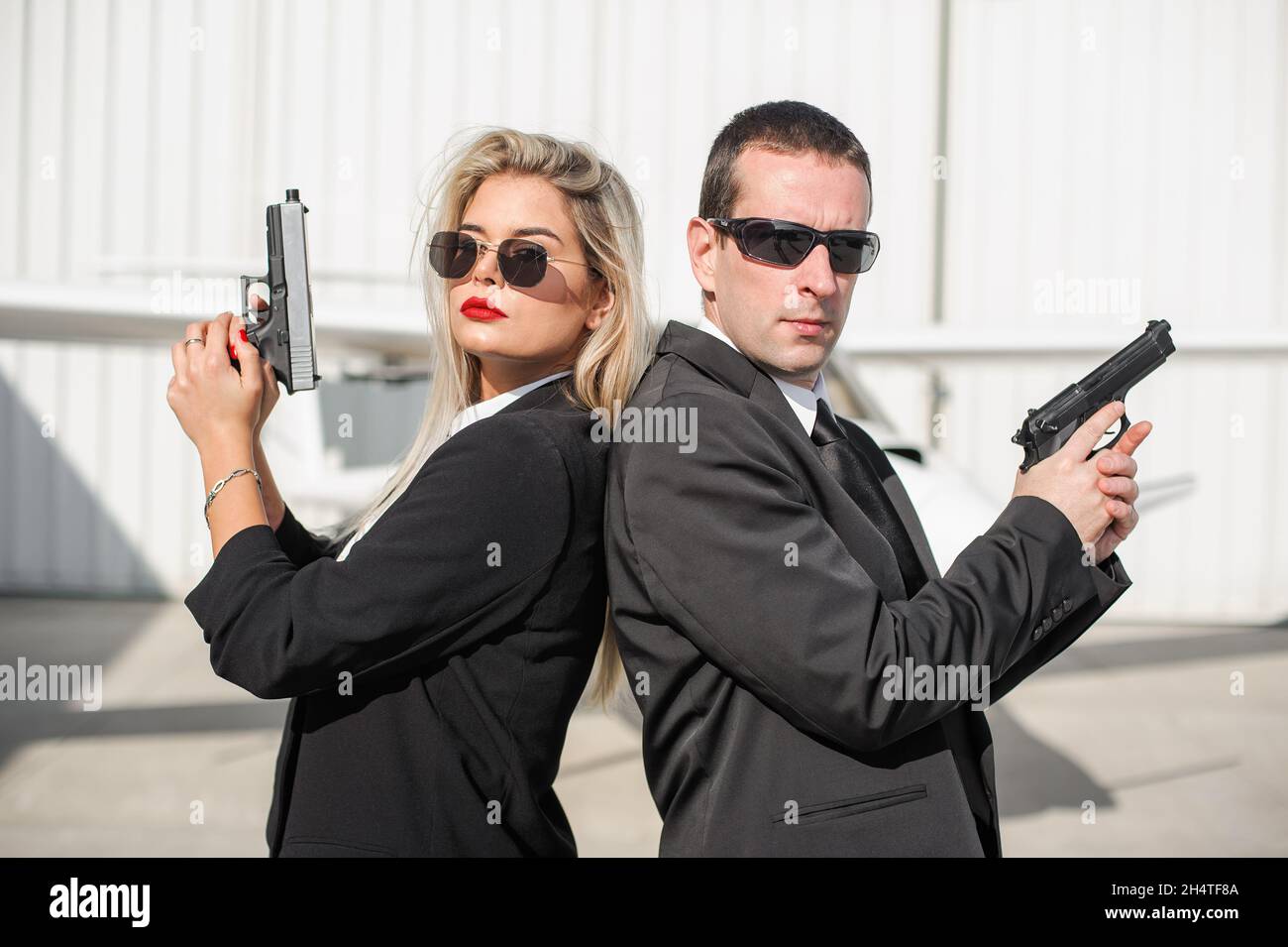 Professional female and male spy agent bodyguards posing with guns. Security police team in civilian black suit with sunglasses Stock Photo