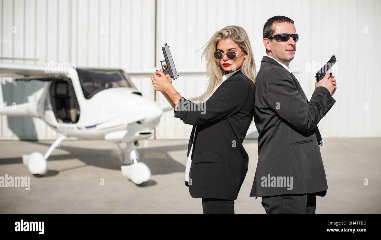 Professional female and male spy agent bodyguards posing with guns. Security police team in civilian black suit with sunglasses Stock Photo