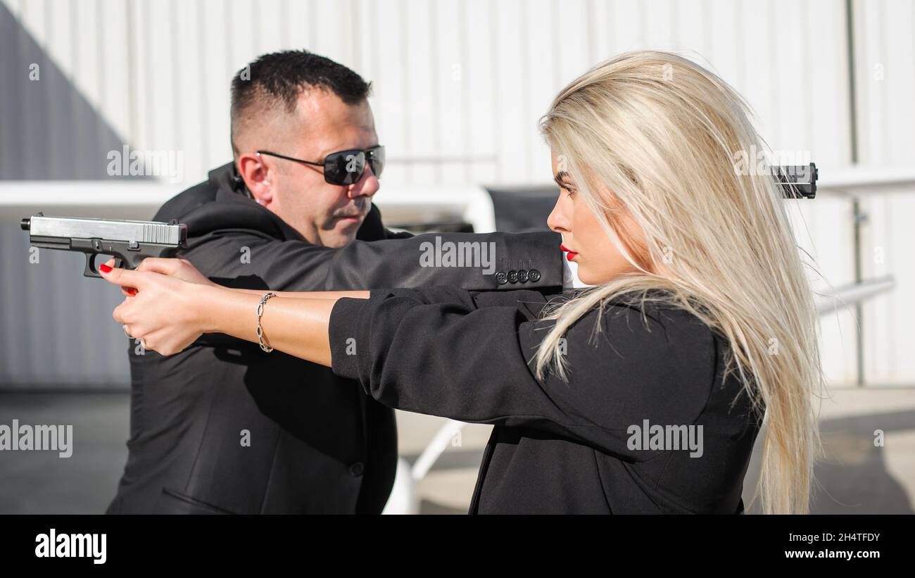 Professional female and male spy agent bodyguards posing with guns. Security police team in civilian black suit with sunglasses Stock Photo