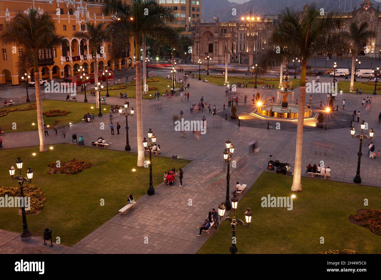 Peruvians in Plaza Mayor at dusk, Historic centre of Lima (World Heritage Site), Peru, South America Stock Photo