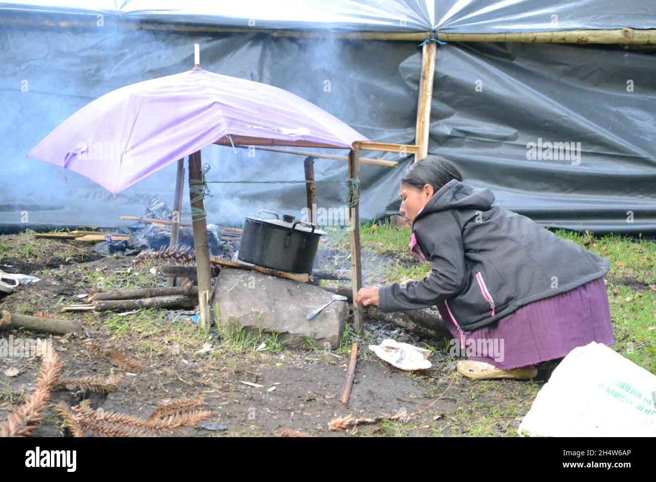 An indigenous girl cooks on a makeshift stove during the almost 30 days of the takeover of Bogota's Parque Nacional by more than 800 indigenous displaced by violence, where they demanded guarantees from the government to be able to return to their territories, after some confrontations with the public force in Bogota, Colombia on October 28, 2021. Stock Photo