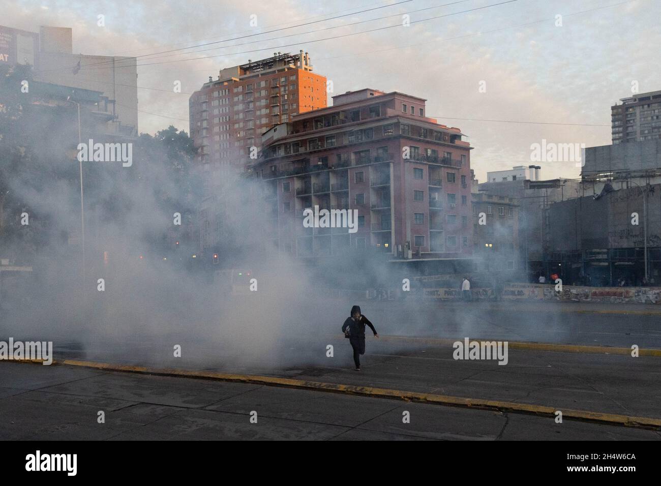 Santiago, Metropolitana, Chile. 4th Nov, 2021. A photographer runs from tear gas bombs during protests against the Sebastian Pinera government in Santiago, Chile. The protests come after the death of a Mapuche person during clashes in the southern region of Bio Bio after the Chilean government declared a state of emergency to reduce violence in that area of southern Chile. (Credit Image: © Matias Basualdo/ZUMA Press Wire) Stock Photo