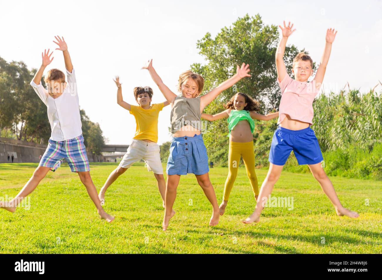 Happy school children jumping on the green lawn in park Stock Photo - Alamy