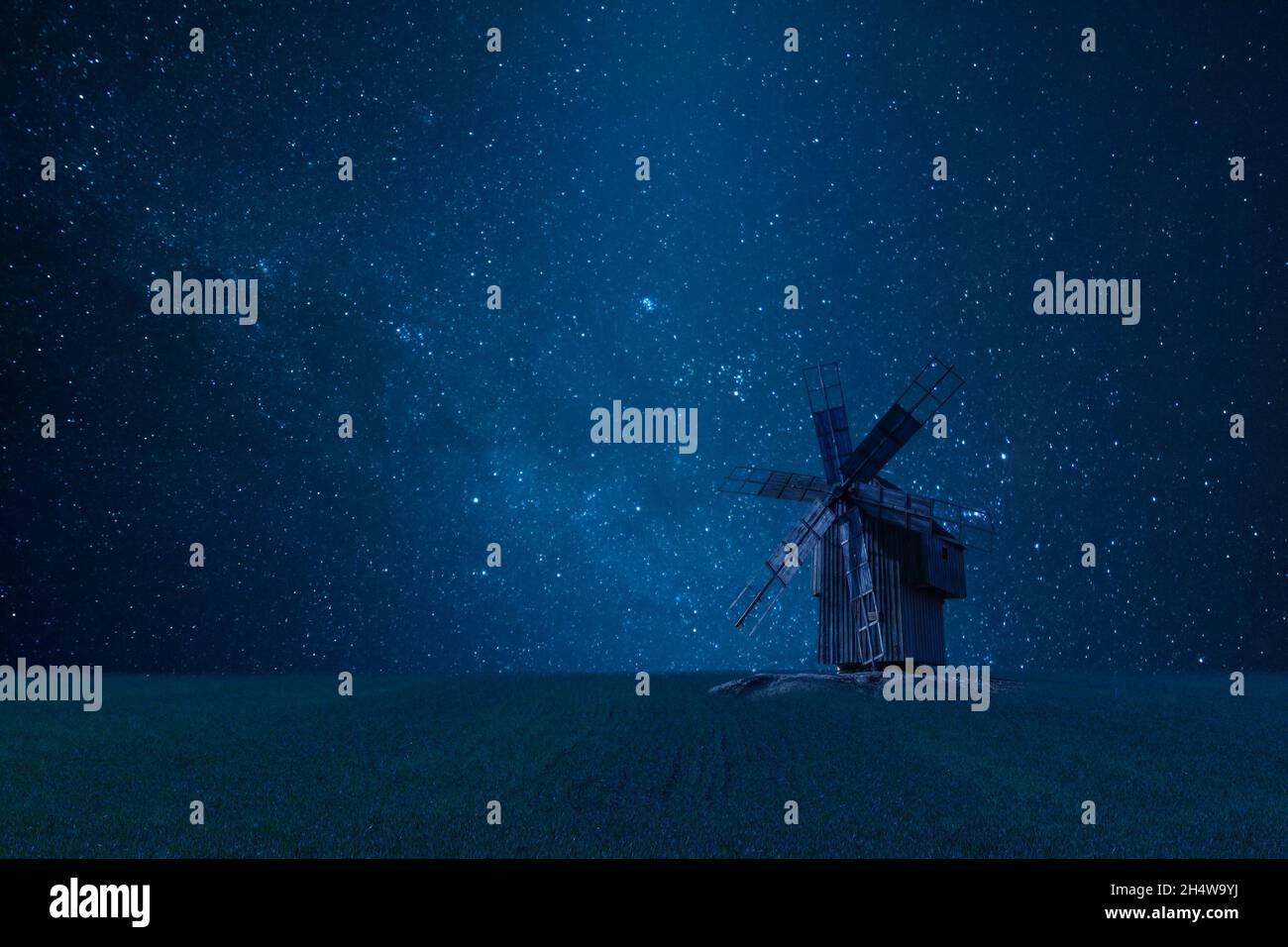 Night landscape with old windmill in field, bright stars in sky, endless galaxy Stock Photo