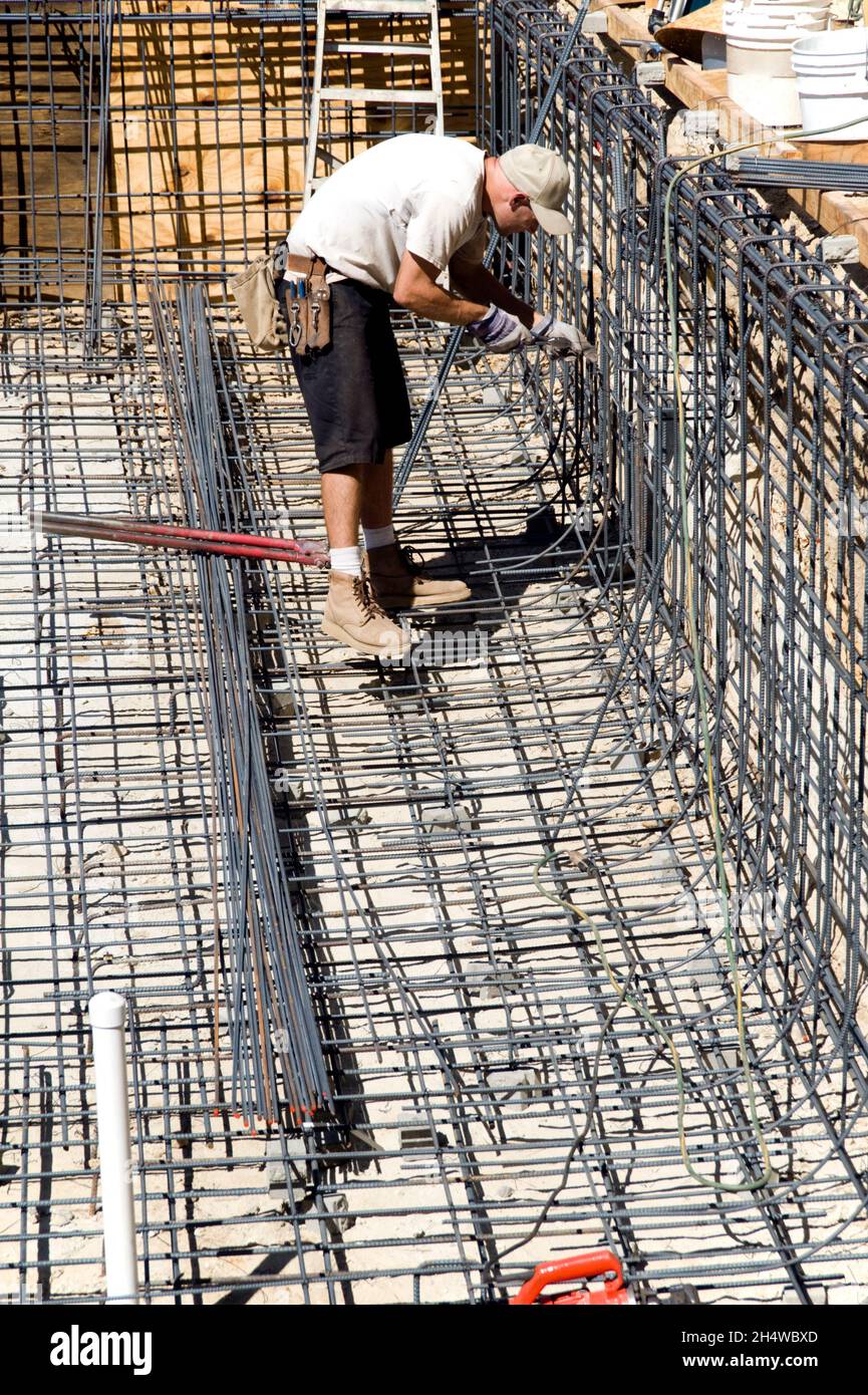 Construction worker tying rebar together to shape the foundation for a new swimming pool Stock