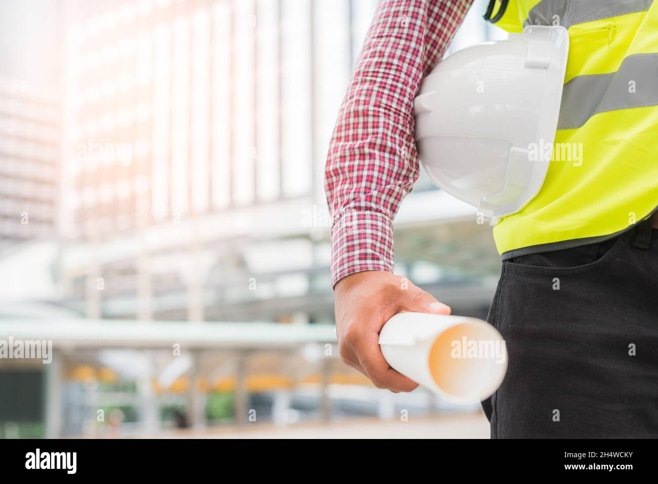 Engineering holding safety helmet on building background. Stock Photo