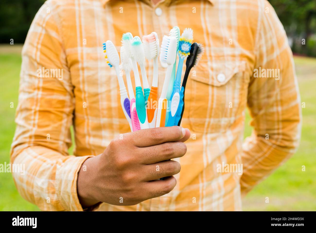 Man holding Old colorful toothbrushes on nature background Stock Photo