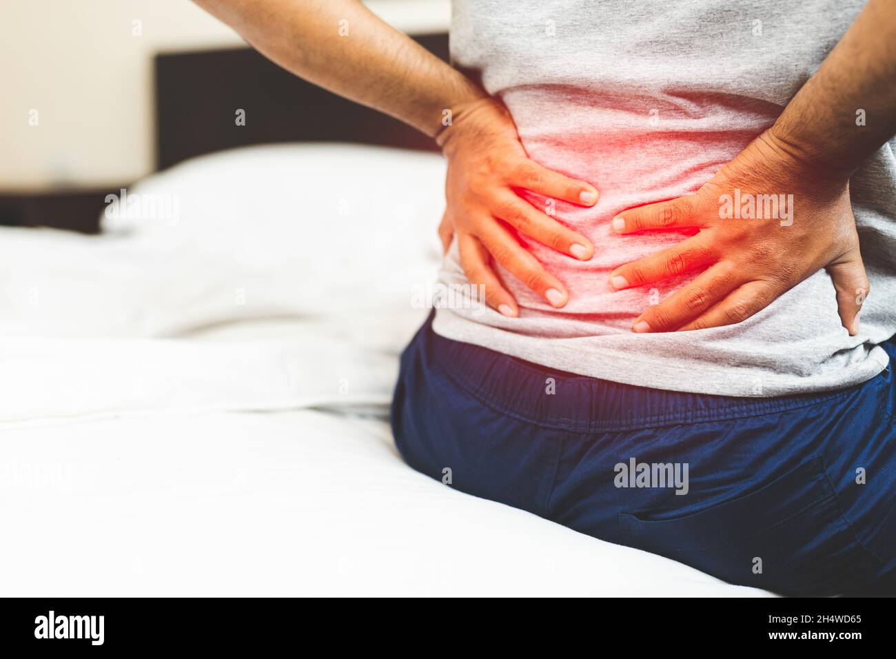 Man suffering from back pain on the bedroom Stock Photo - Alamy