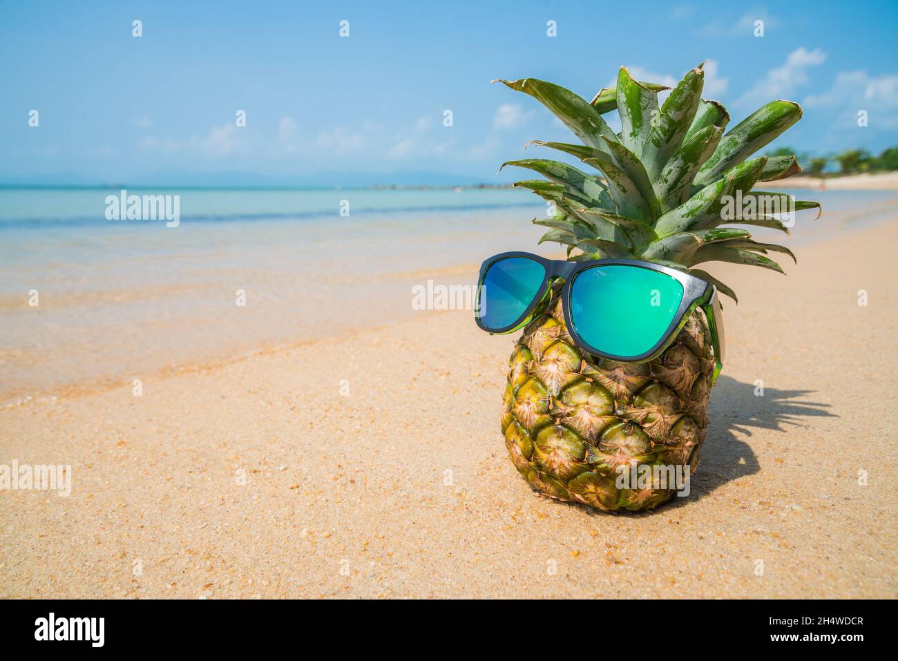 Pineapple with sunglasses on tropical beach background. Summer concept