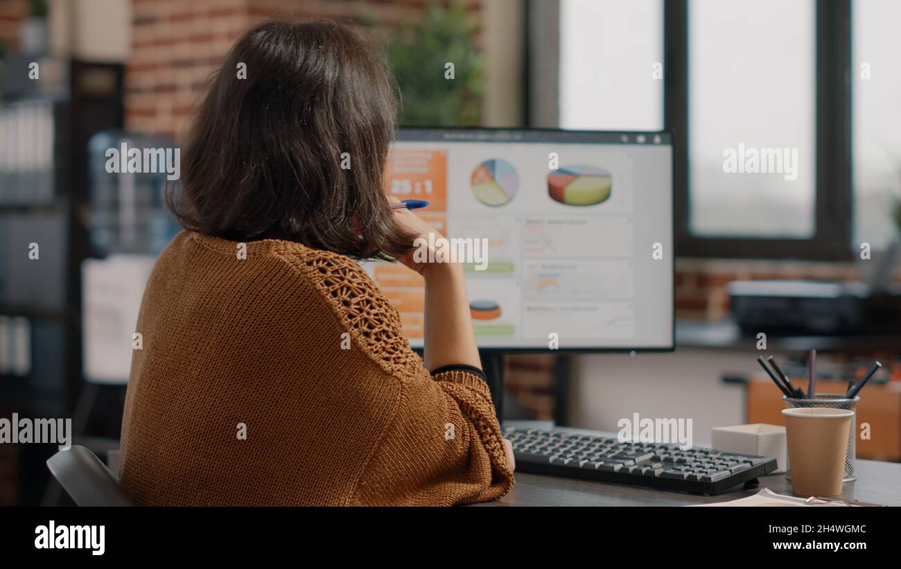 Business woman analyzing rate charts on computer and files to plan ...