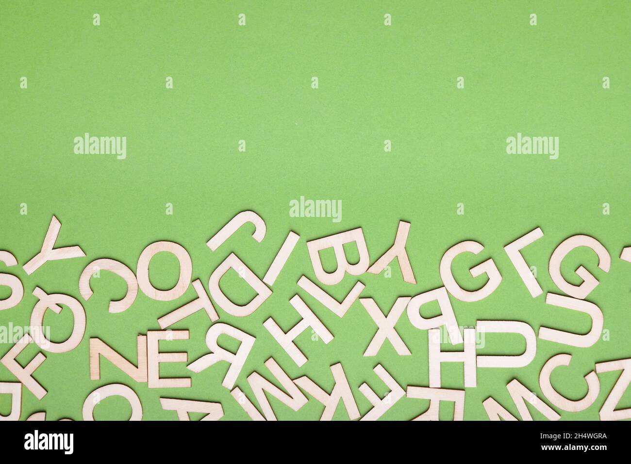 hodgepodge of wooden letters on green paper background Stock Photo