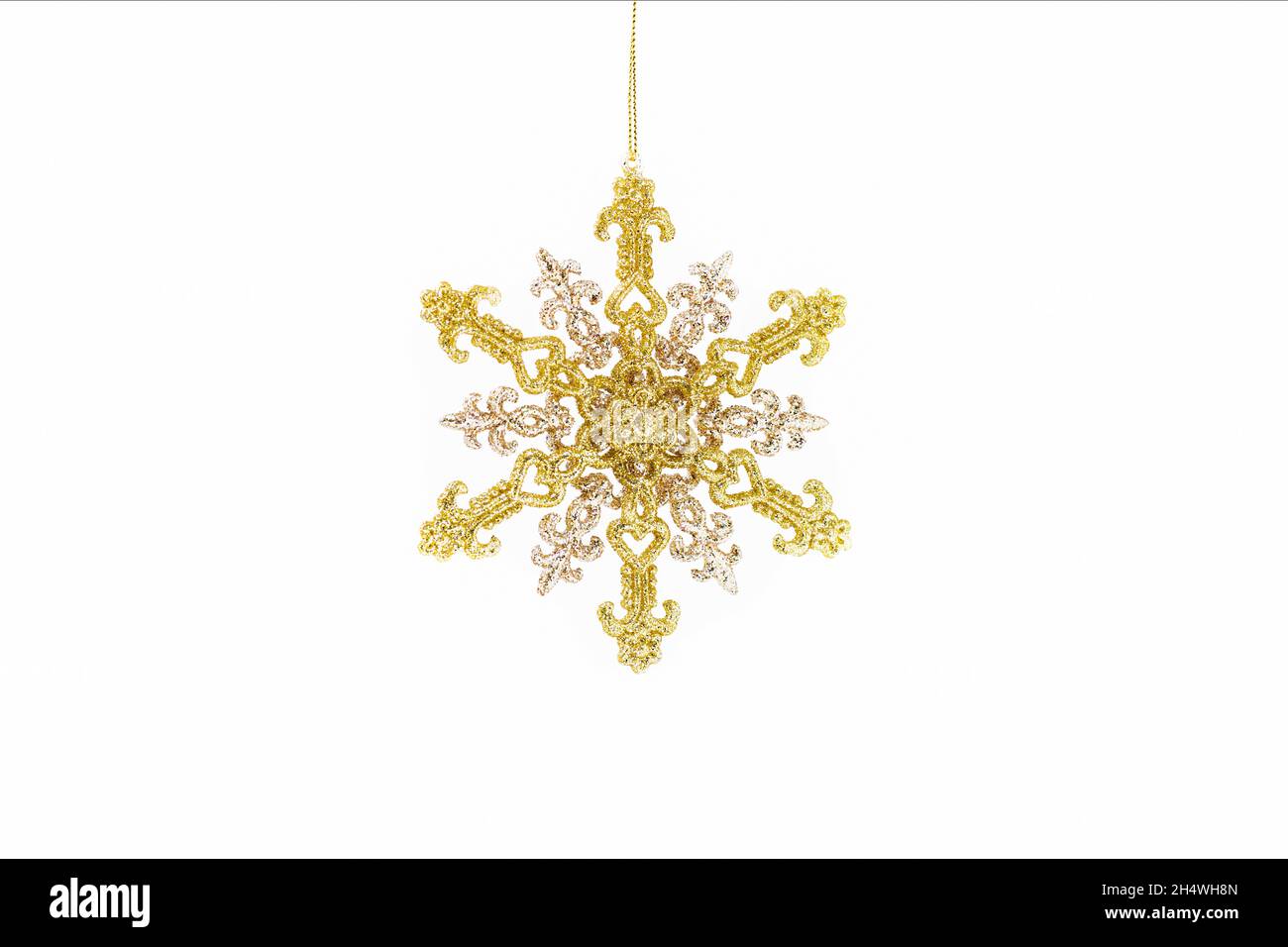 Snowflake. Snowflake on White. Vintage golden christmas snowflake hangs isolated on a white background. Golden Christmas Glitter. Stock Photo
