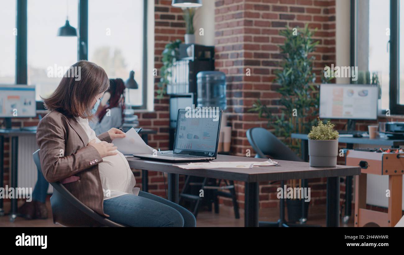 Expectant Person Computer Pregnant employee with face mask using laptop to work on successful ...
