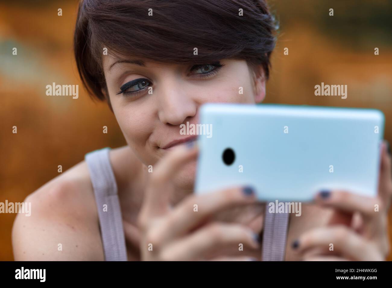 Sceptical young woman looking at her mobile phone with a wry smile and expression of disbelief in a close up cropped portrait Stock Photo