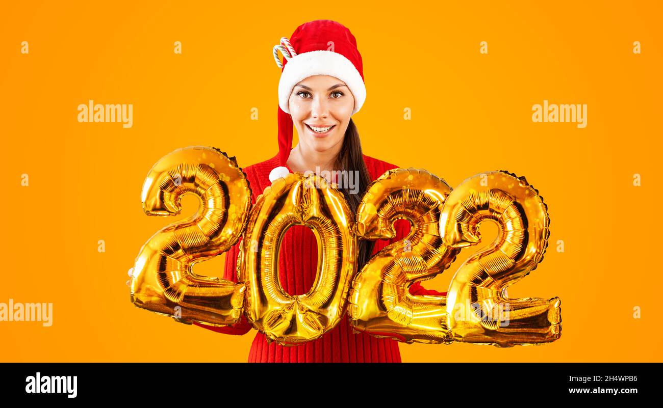 New Year 2022 Gold Balloons. Young woman in Santa Claus hat having ...