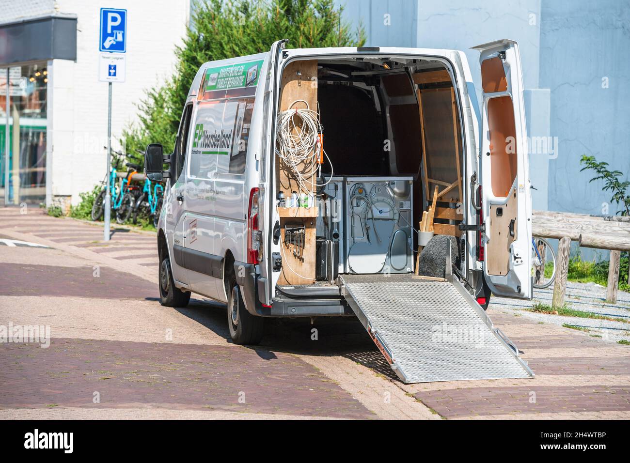 White electric Volkswagen transporter van transporting wash dryer and