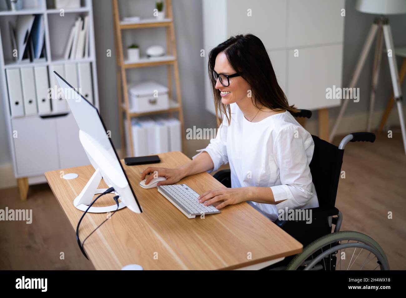 Person With Disability In Wheelchair Working On Computer Stock Photo