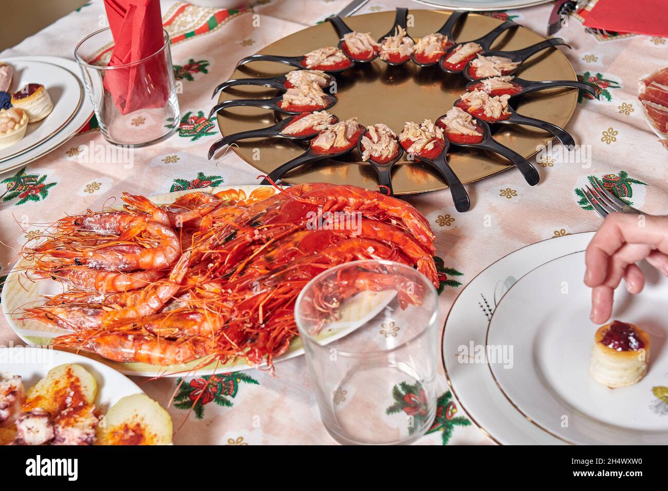 Grilled shrimp platter and plate of appetizers on a table with a tablecloth with Christmas motifs. preparation of the family christmas dinner. Stock Photo