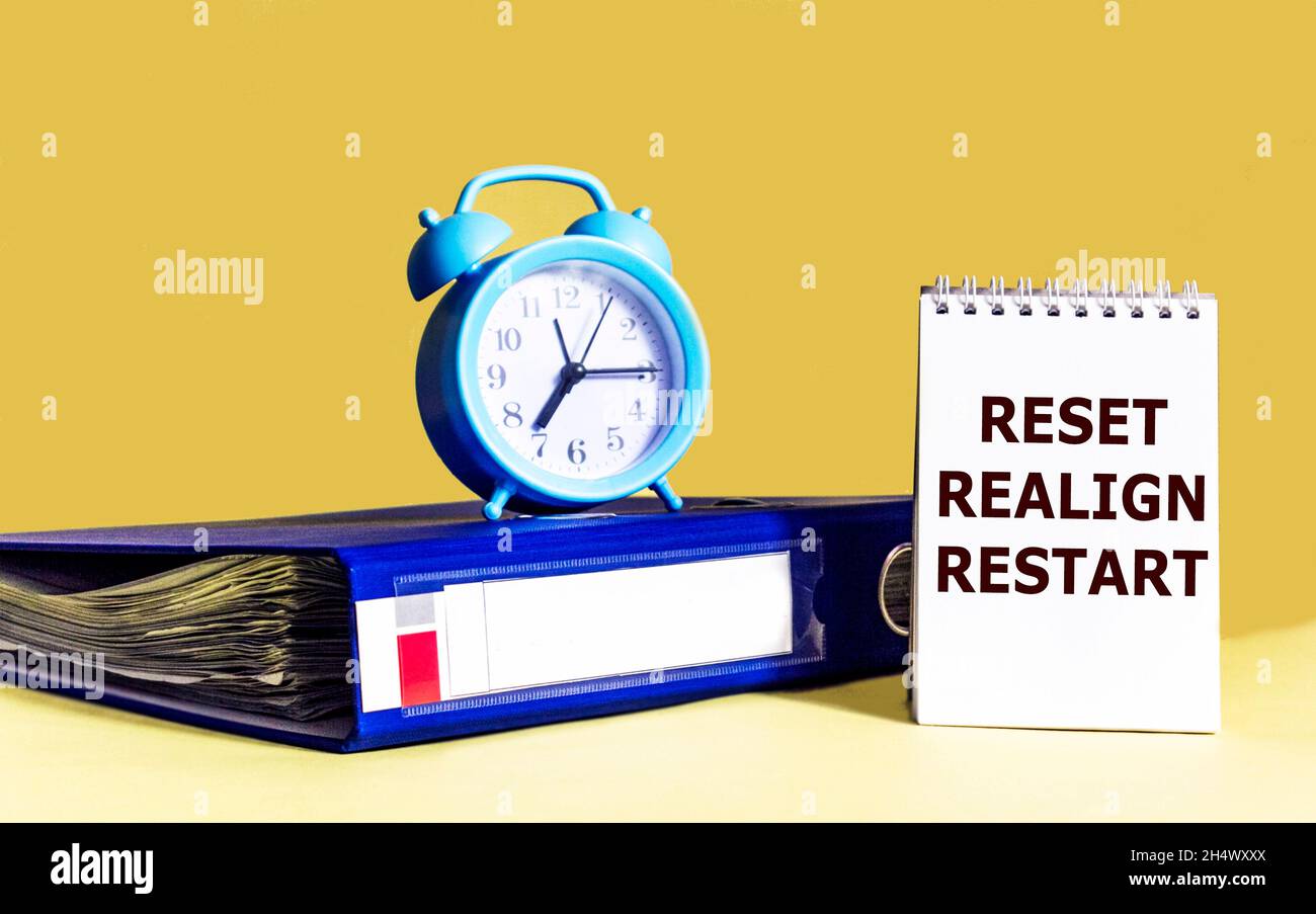RESET, RESETTING, RESTART written on, notepad, next to document folder and clock. Business concept. Stock Photo