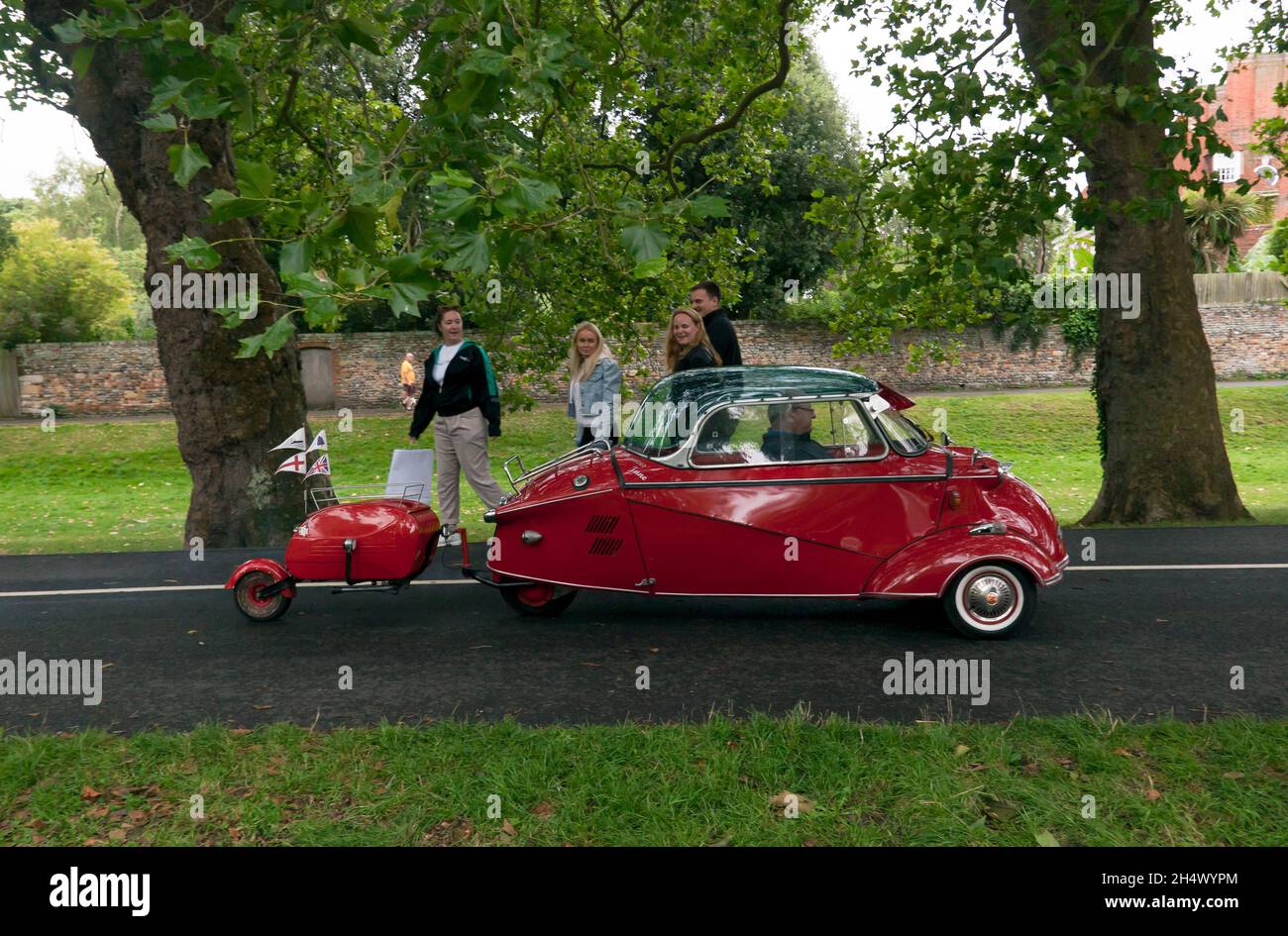 Spectators watching  a Red, 1961,  Messerschmitt KR200,  with matching trailer,  leaving the show ground  at the end of the Sandwich Festival Classic Car Show 2021 Stock Photo