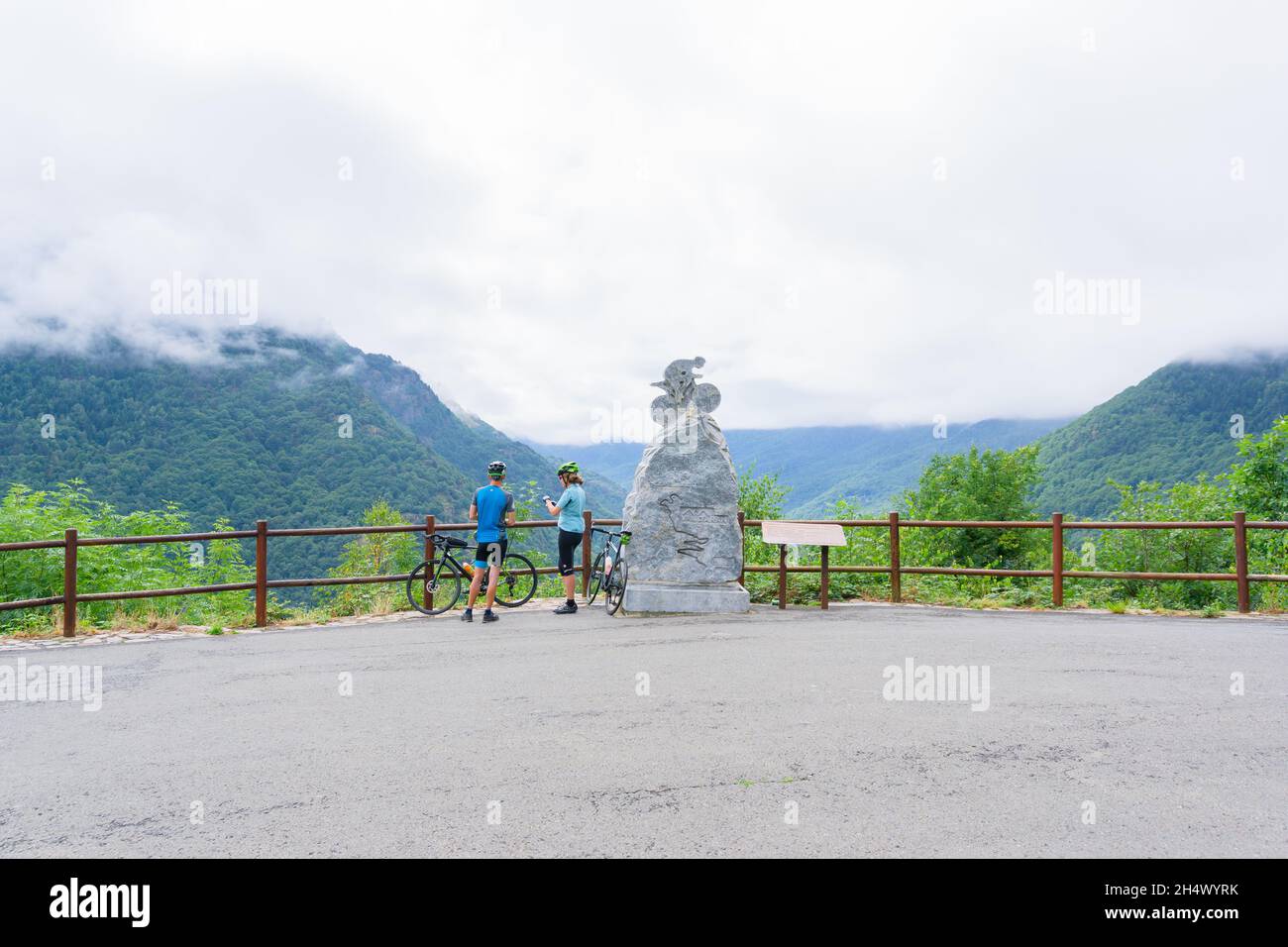 LLEIDA, SPAIN - JULY 28, 2021: Image of a man and a woman cyclists resting on top of the mountain in a viewpoint next to a tour de france monument in Stock Photo