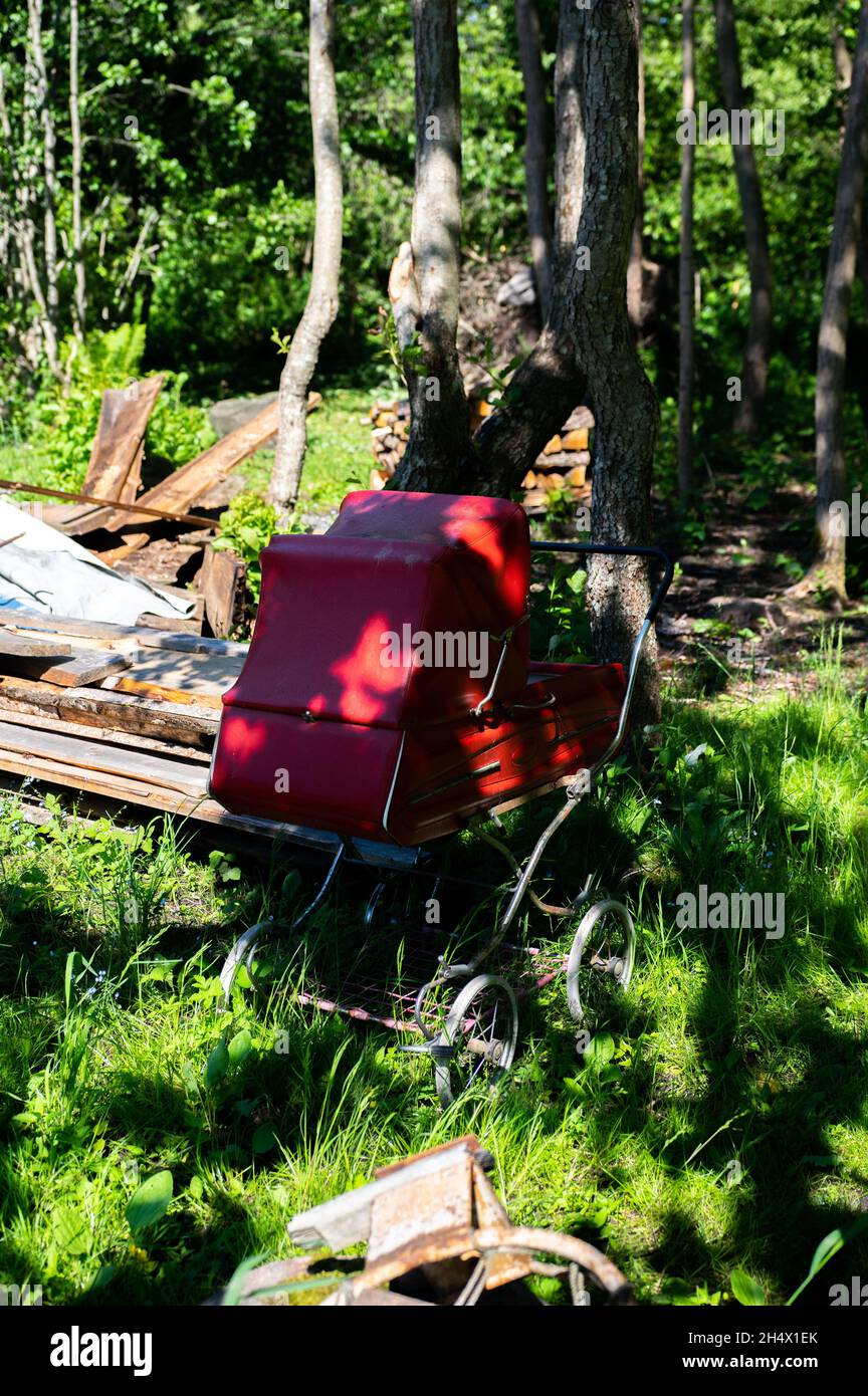 Vertical shot of an old red baby carriage in the yard Stock Photo