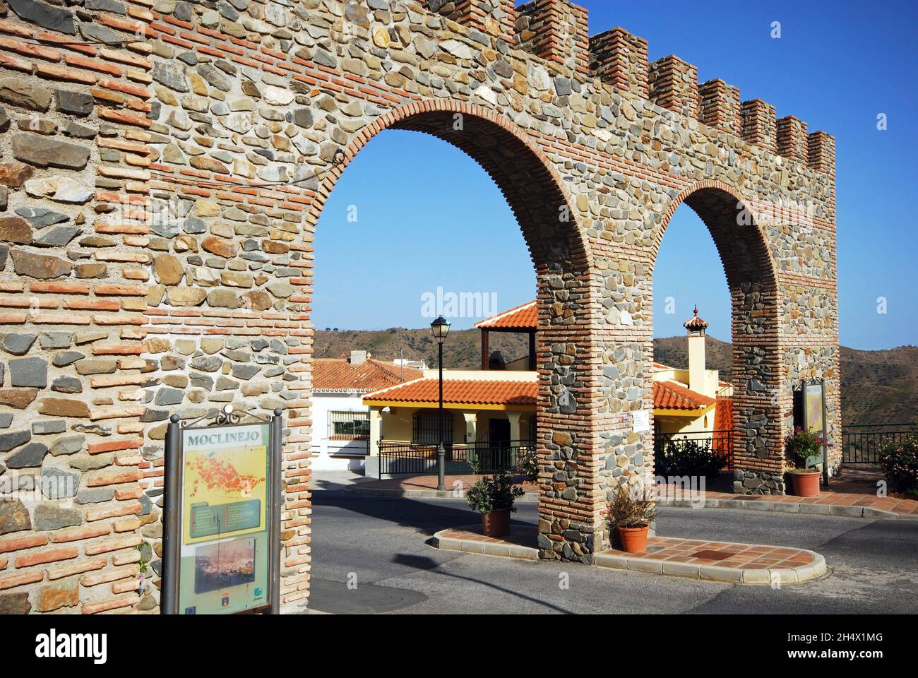 View through the castle style entrance arch, Whitewashed village (pueblo blanco), Moclinejo, Spain. Stock Photo