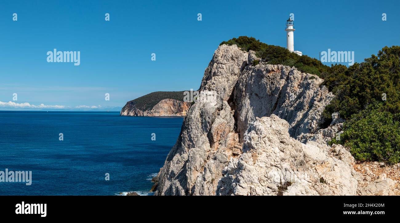 Panorama Ionian sea island steep rocky cliffs with lighthouse hidden in greenery on a bright clear blue sky in Greece. Scenic travel destination. Lefk Stock Photo