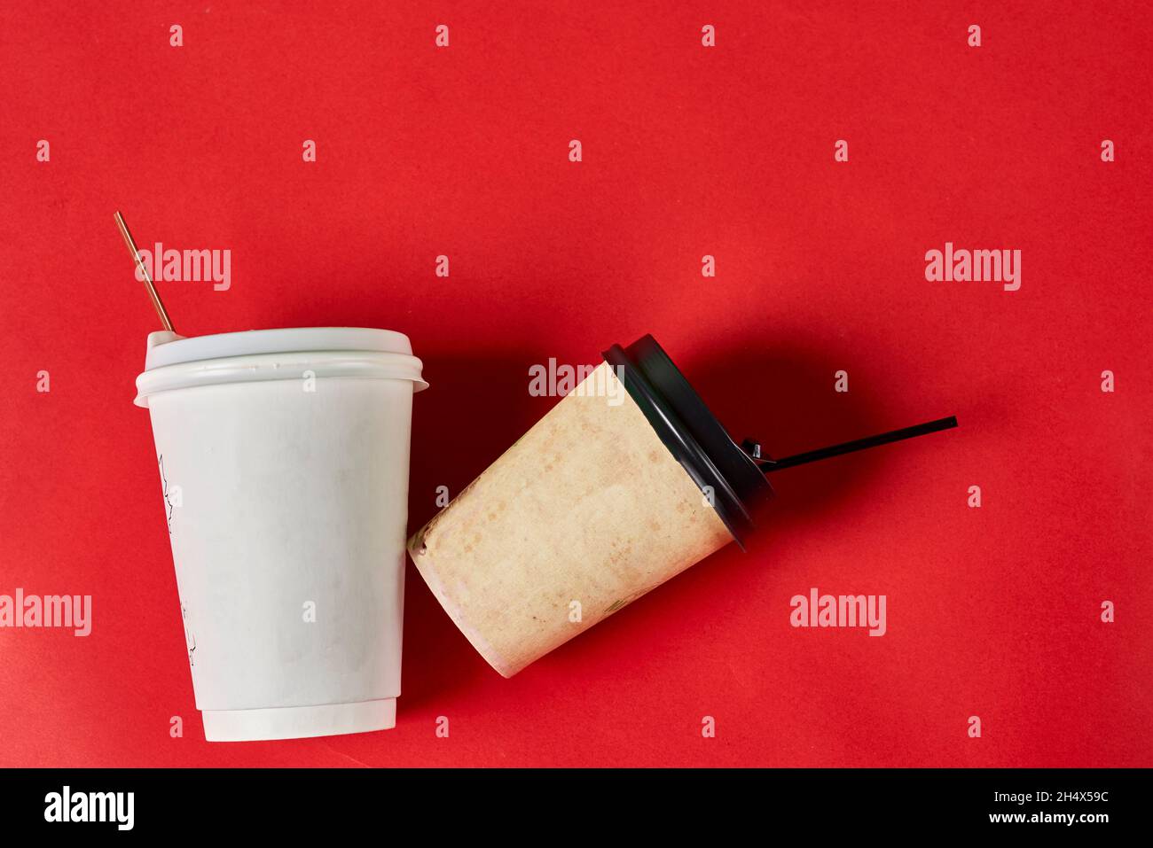 Two singleuse plastic coffee cups on red background with copy space