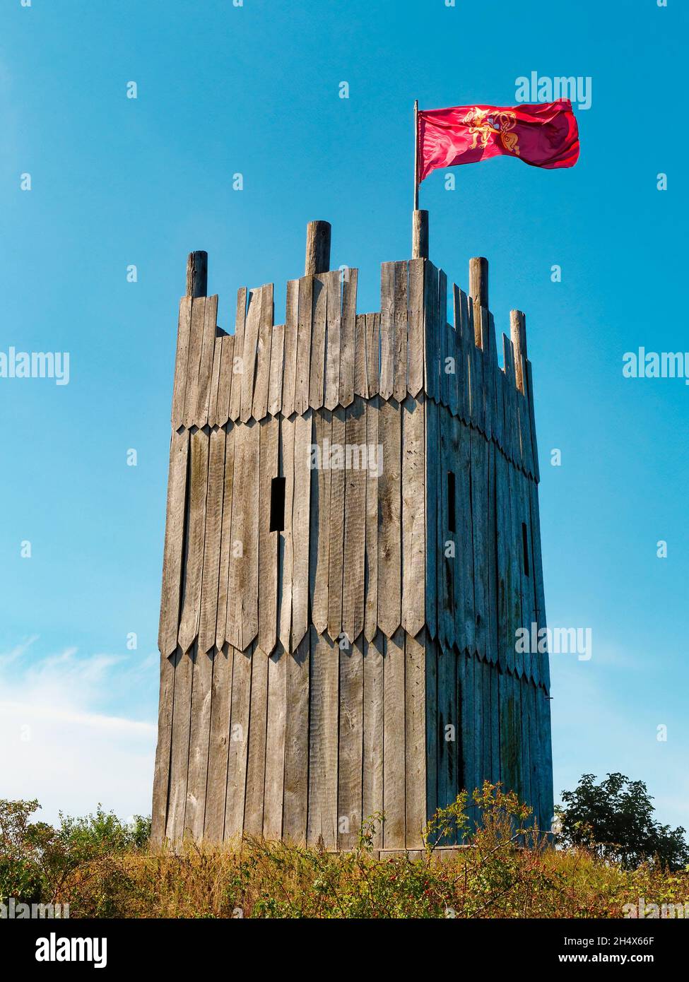Wooden tower of viking village with viking flag waving against clear