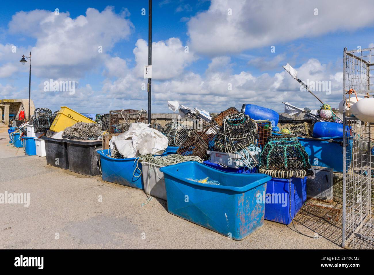 Plastic tubs of rope and fishing net and Lobster Crab and Prawn pots stacked on the quay at the working harbour in Newequay on the North Cornwall coas Stock Photo