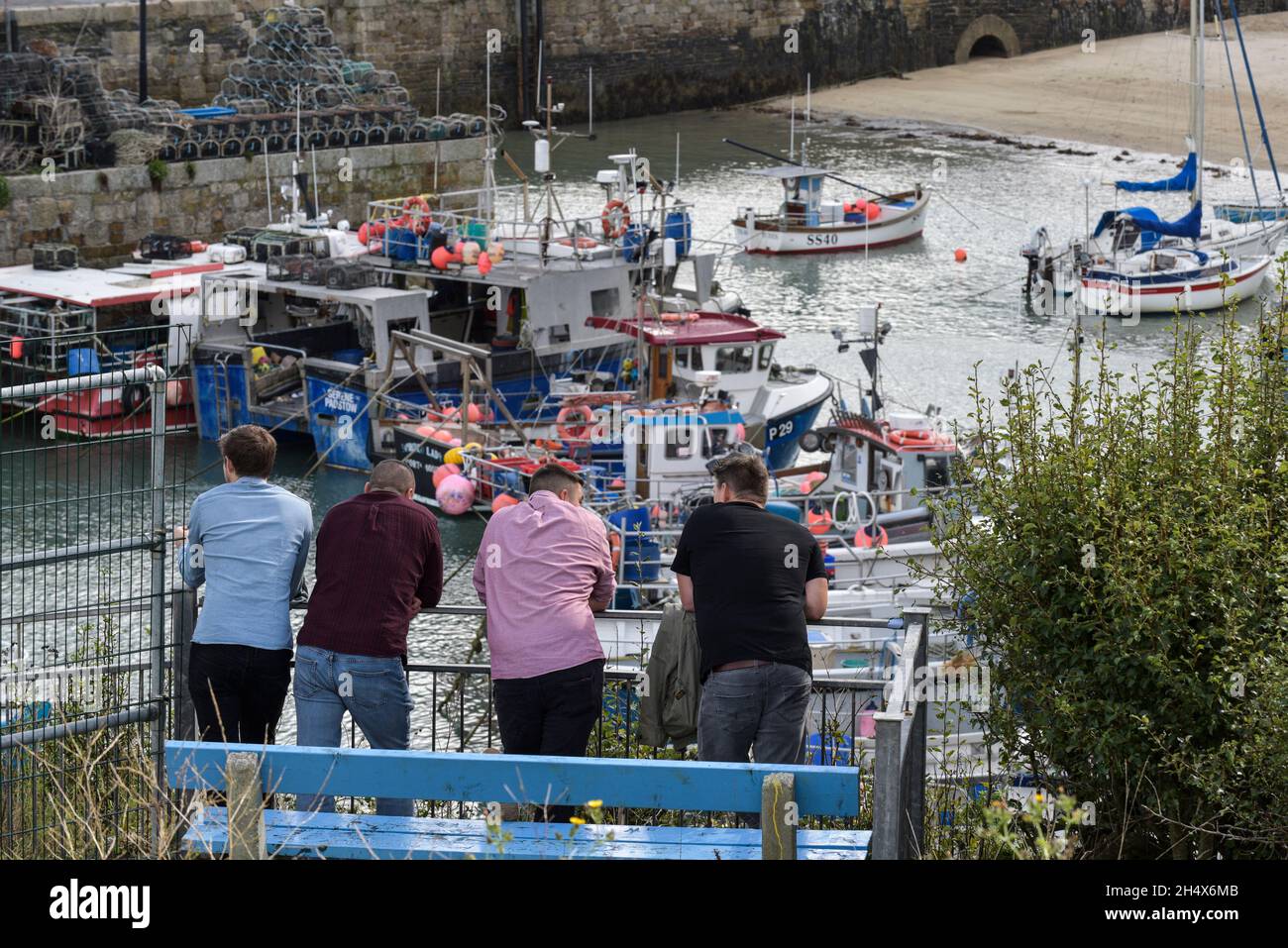 A group of male holidaymakers relaxing and looking out over Newquay Harbour in Cornwall. Stock Photo
