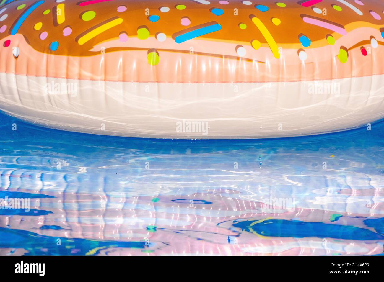 A colourful inflatable plastic ring floating in an outdoor pool. Stock Photo