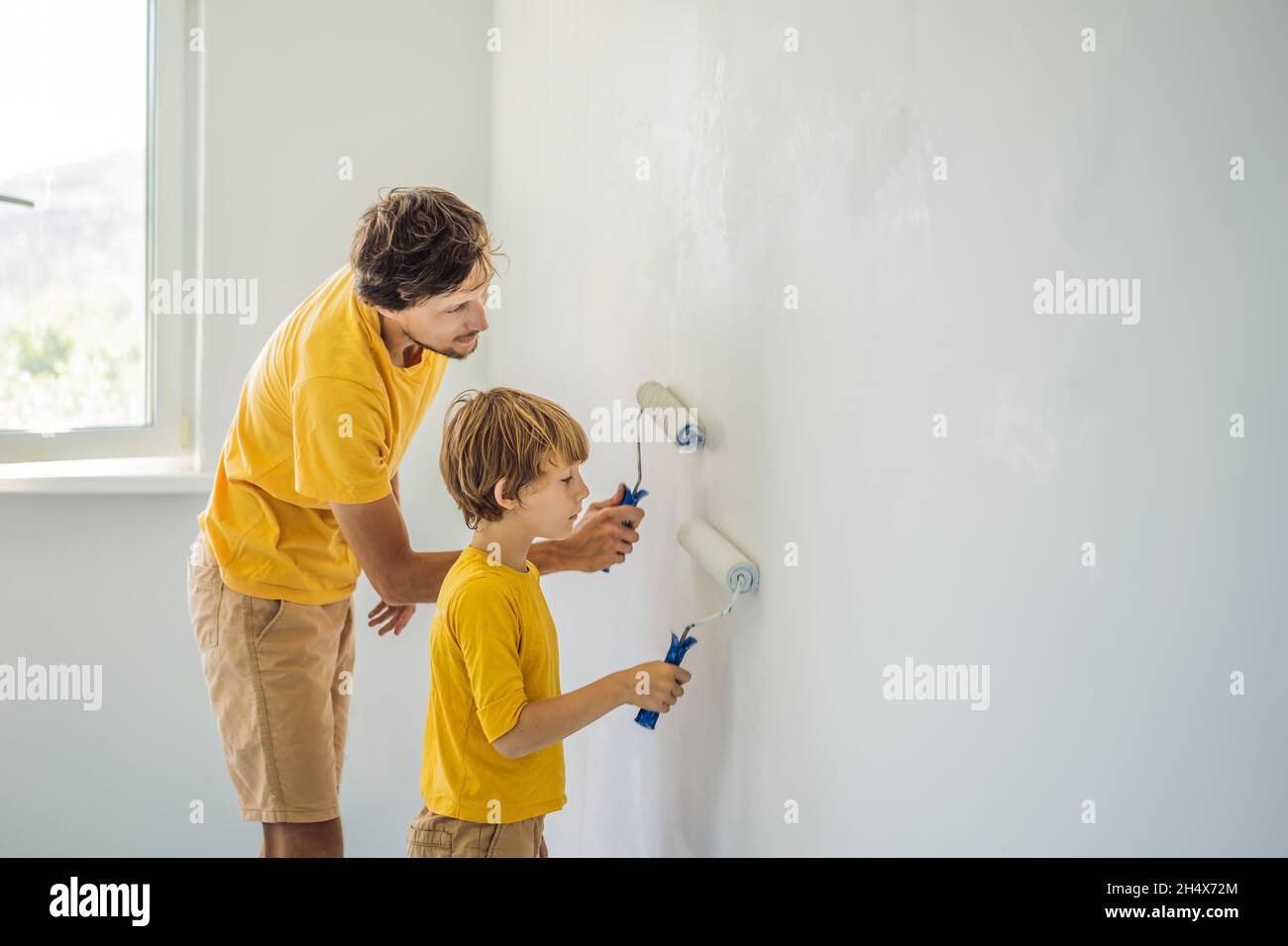 Father and son painting a wall in their home do it in the course of ...