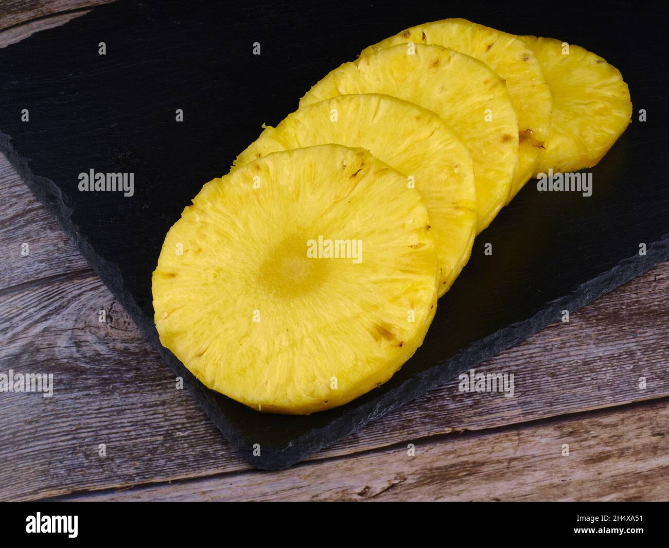 Sliced pineapple on dark stone. Wood table Stock Photo