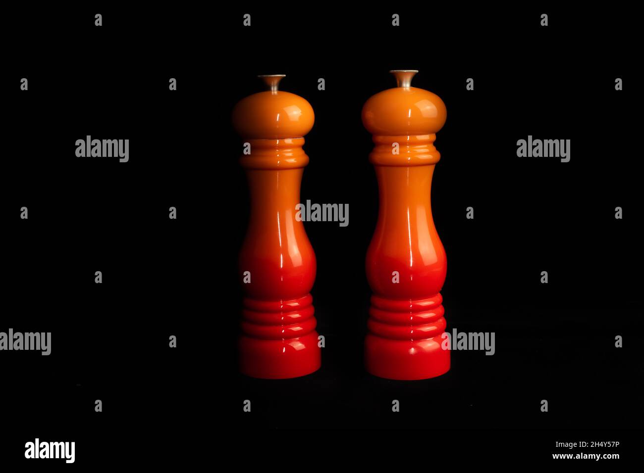 Front view of two luxurious salt and pepper mills and grinders isolated on a black background. Stock Photo