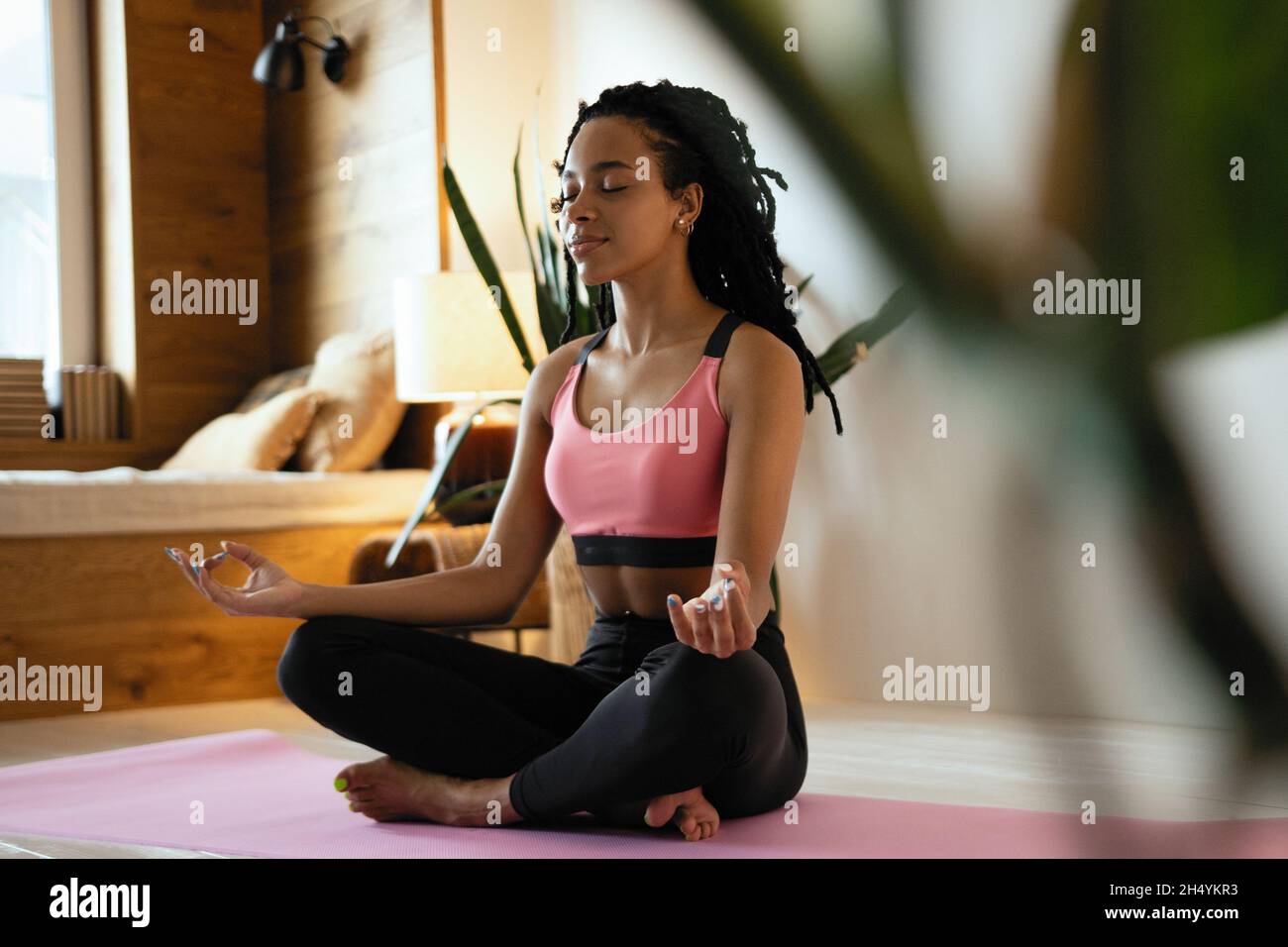 Young black woman doing yoga at home in the lotus position Stock Photo ...