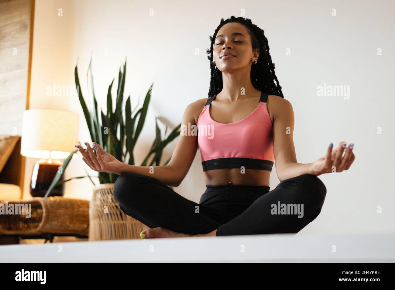 Young black woman doing yoga at home in the lotus position Stock Photo
