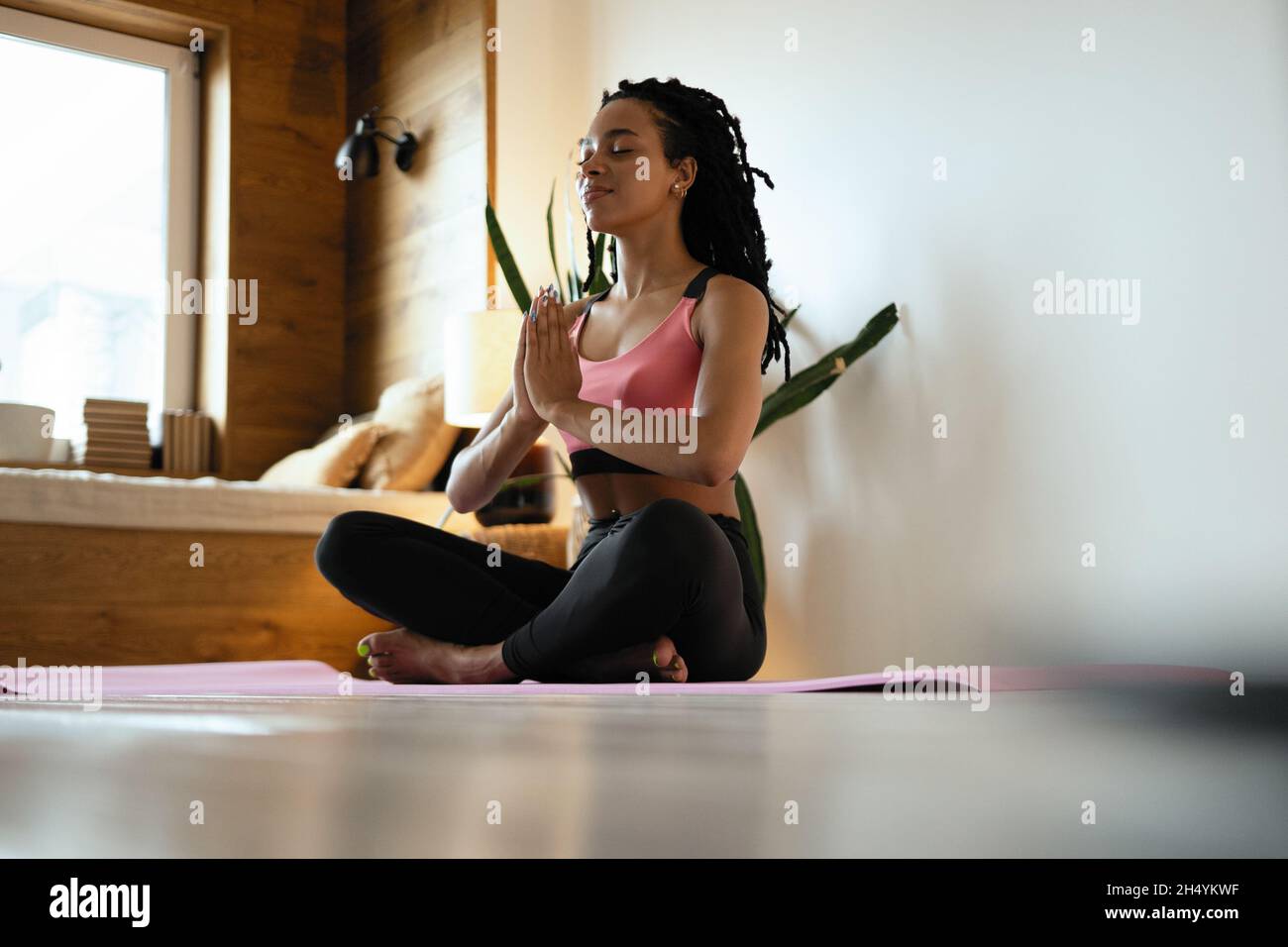 Young black woman doing yoga at home in the lotus position Stock Photo