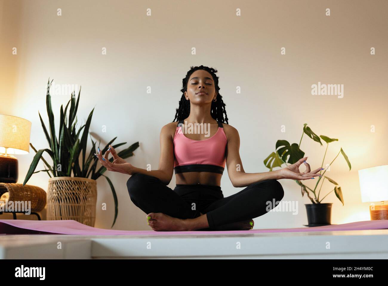 Young black woman doing yoga at home in the lotus position Stock Photo ...