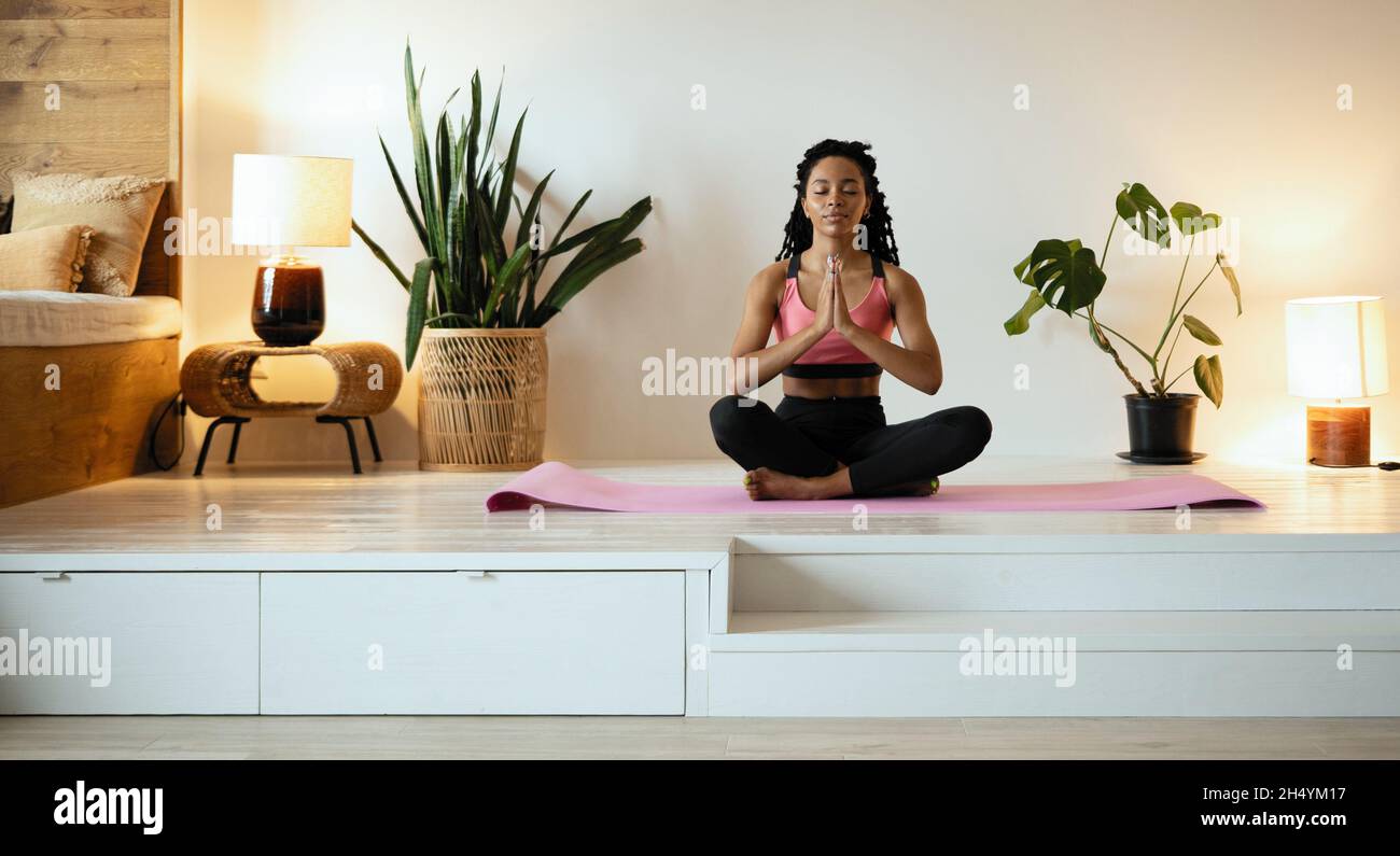Young black woman doing yoga at home in the lotus position Stock Photo ...