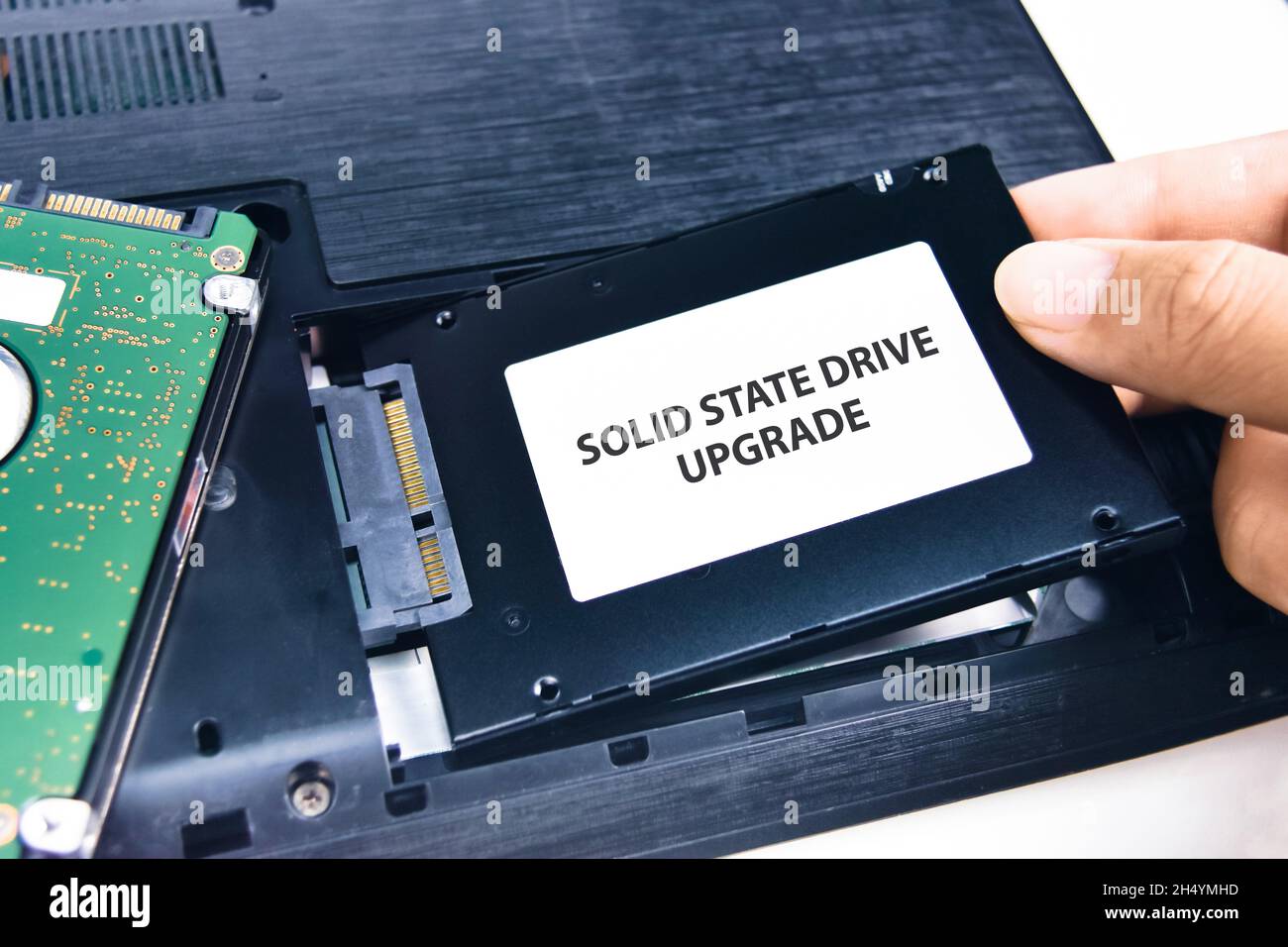 A technician installs a Solid State Drive (SSD) in a laptop computer Stock Photo