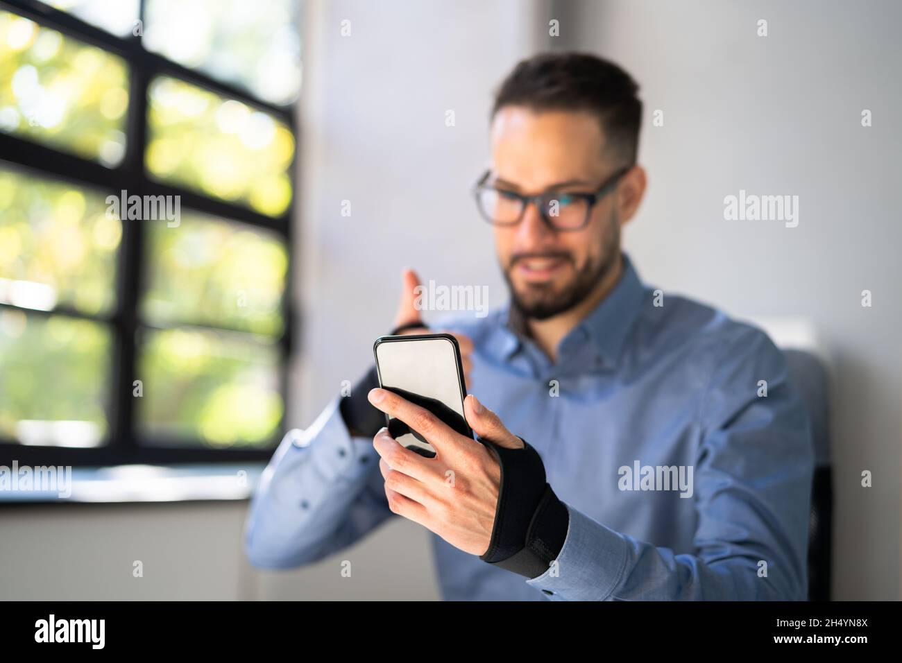Holding Mobile Phone Using Wrist Strap Against Elbow Pain Stock Photo