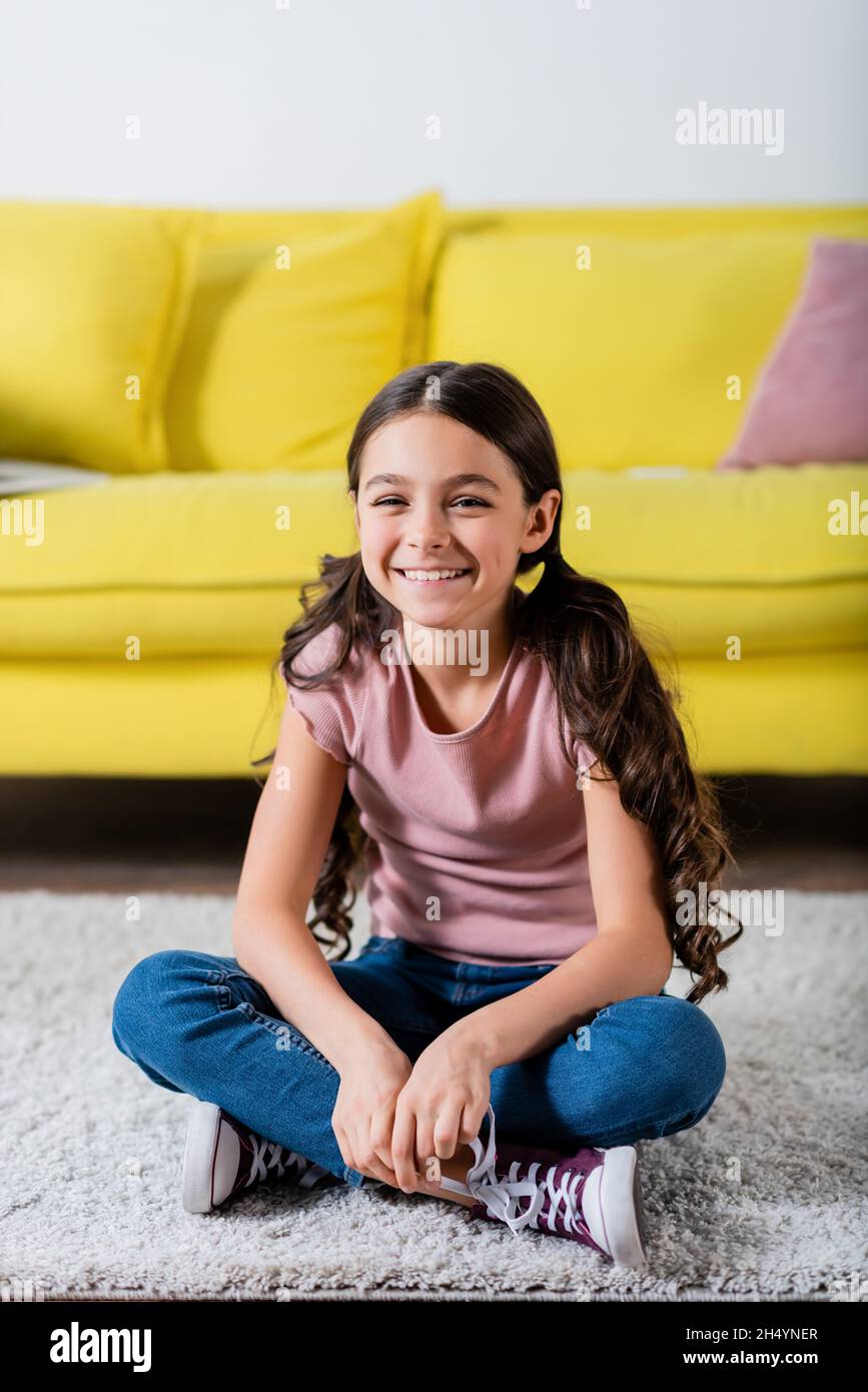 preteen girl smiling while sitting on carpet in living room Stock Photo ...
