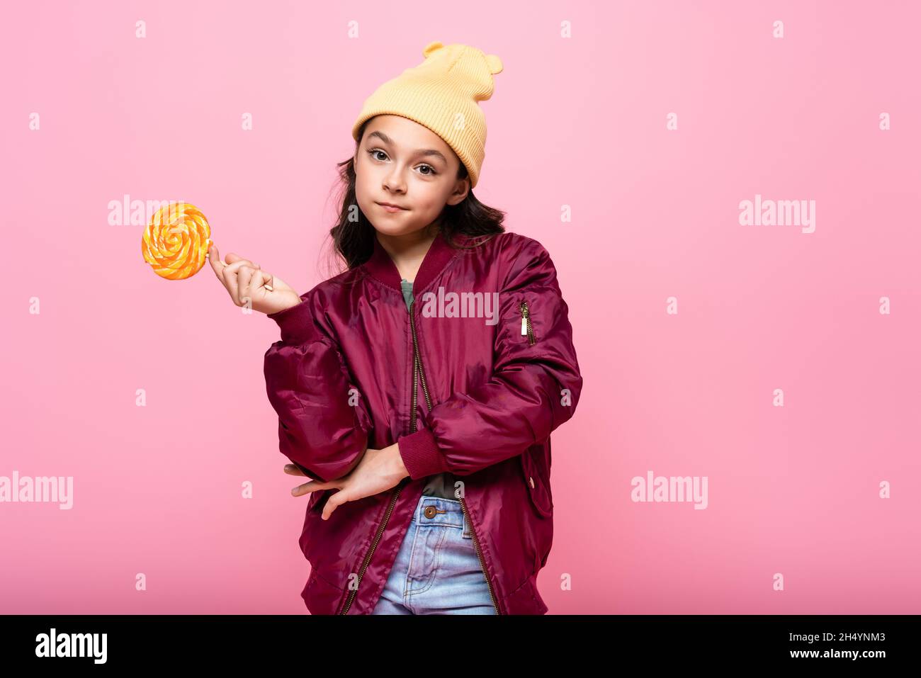 stylish preteen kid in winter outfit holding lollipop isolated on pink Stock Photo