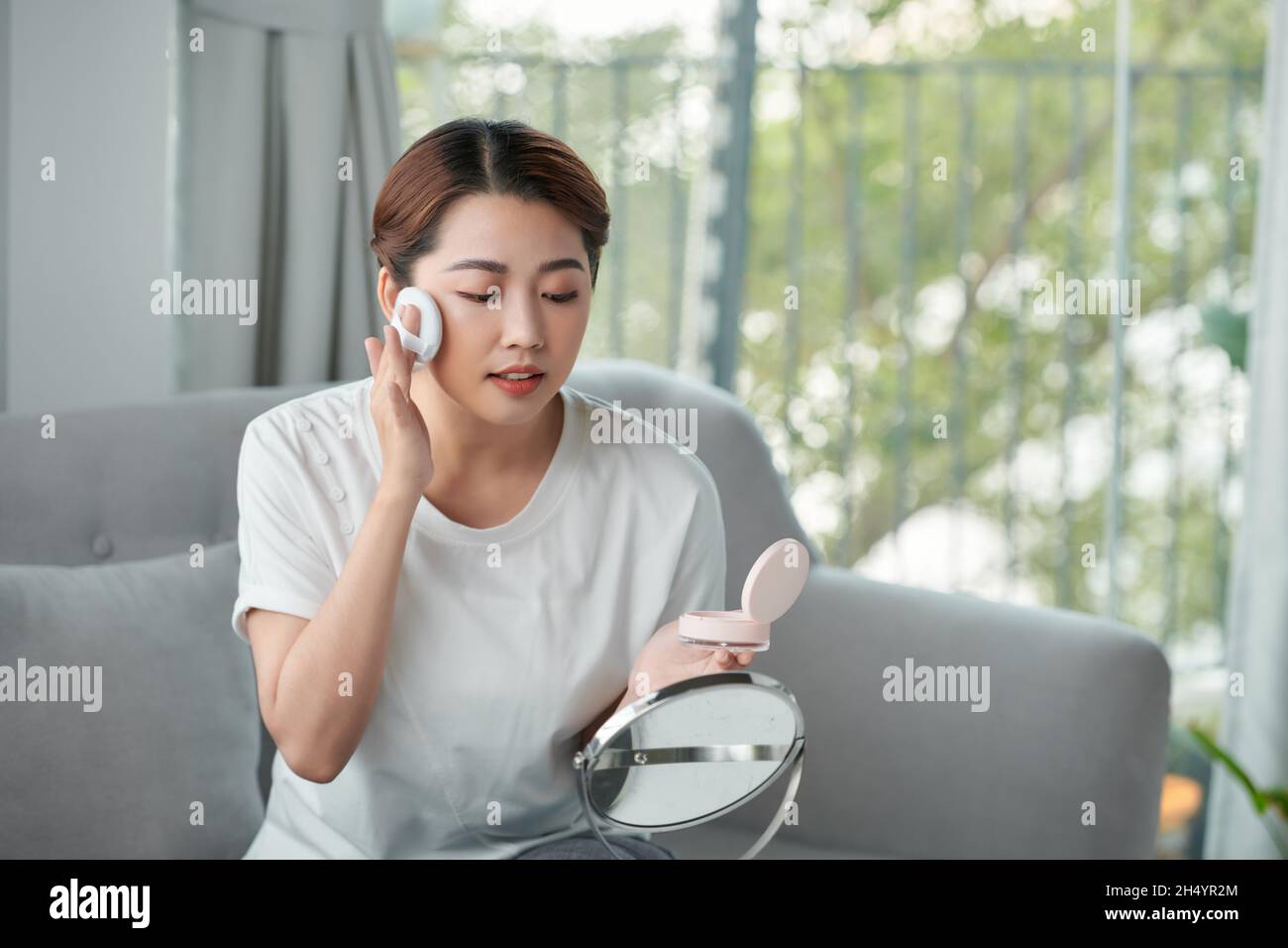 Pretty asian woman applying powder foundation on her face Stock Photo