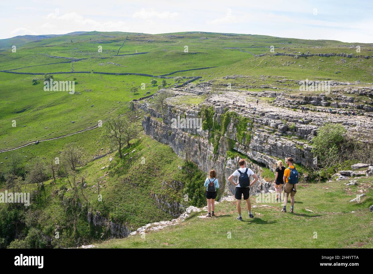Young people countryside, view in summer of a group of hikers in the Yorkshire Dales pausing to look at Malham Cove in North Yorkshire, UK Stock Photo