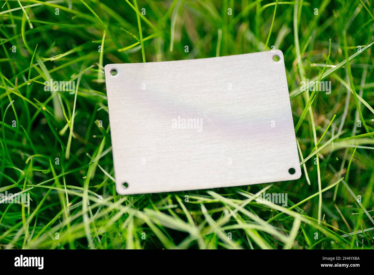 creative layout composition frame made of green grass lawn with square leather patch for clothing for factory flat lay and copy space for logo Stock Photo