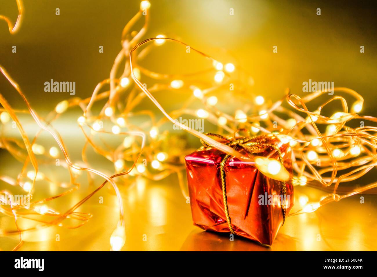 Gift in red wrapping paper. New Guidance background with gift and garland. Stock Photo