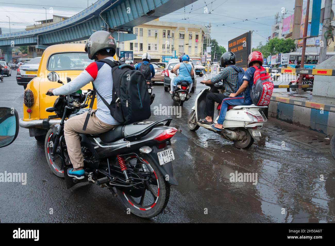 Kolkata, West Bengal, India - 6th August 2019 : Yellow cab, motorbike and scooters, passing below AJC Bose road flyover, busy city traffic of Kolkata Stock Photo